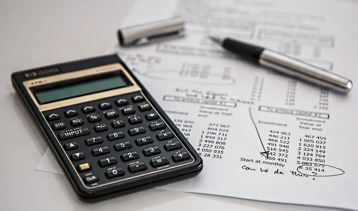 Calculator and ballpoint pen resting on printed financial figures