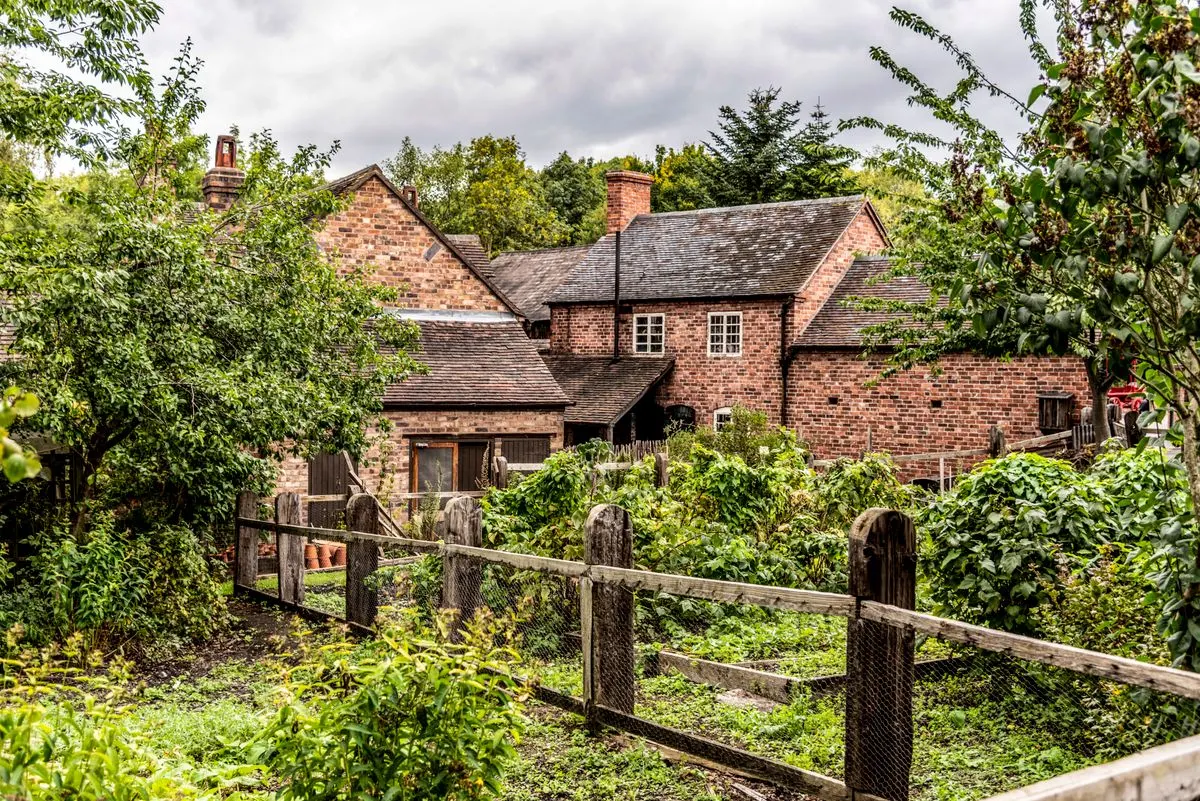 English brick cottage with a garden and wooden fence