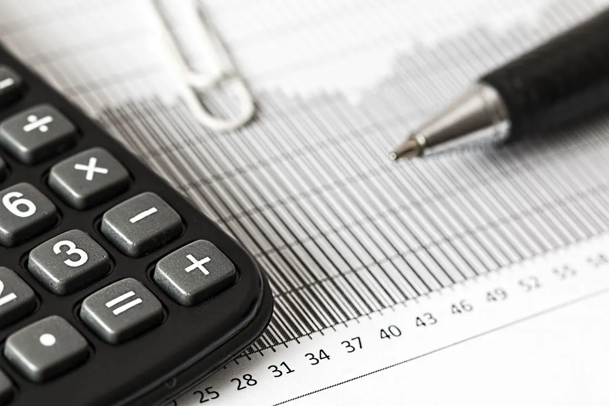 Calculator and pen resting on a printed bar chart