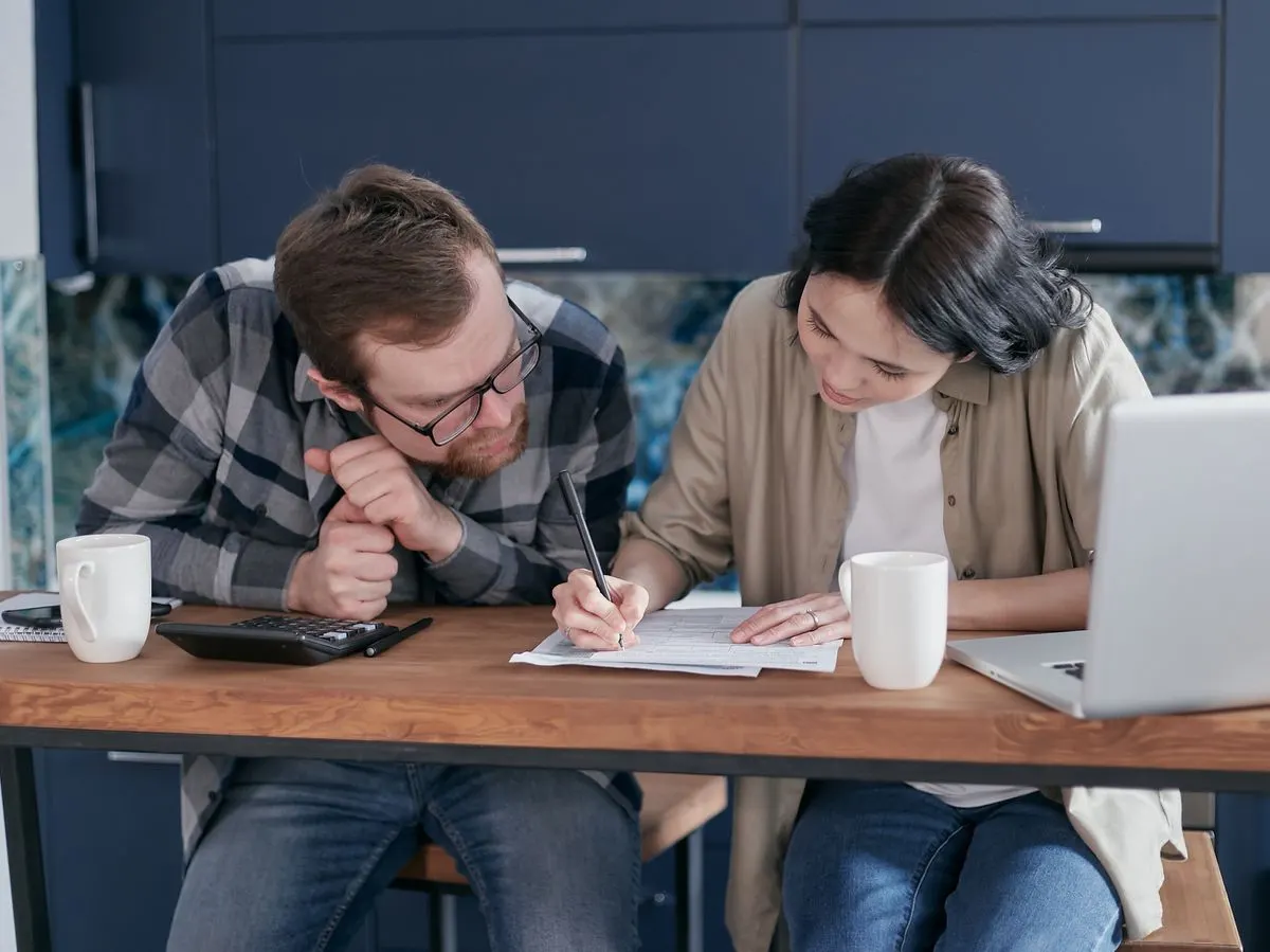 Couple working through paperwork together at a wooden kitchen table
