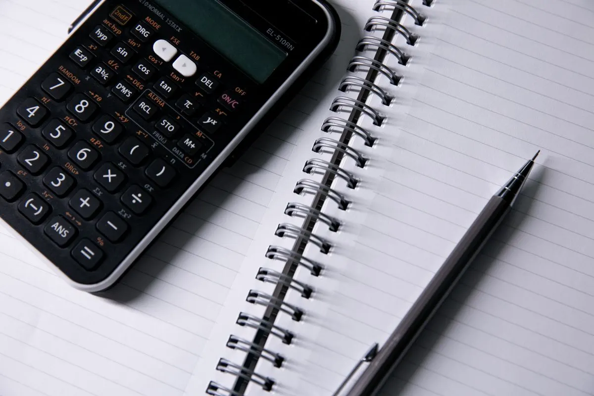 Open notebook, calculator and pen on a desk