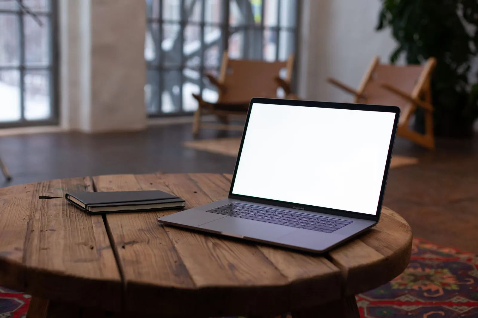 Open laptop and a notebook on a rustic wooden table in soft natural light