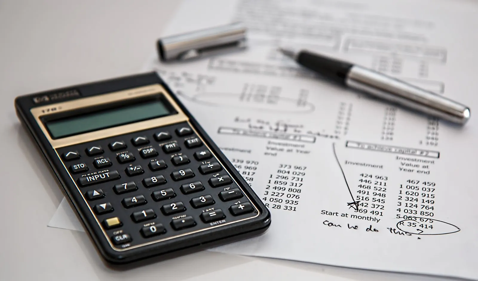 Calculator and ballpoint pen resting on printed financial figures