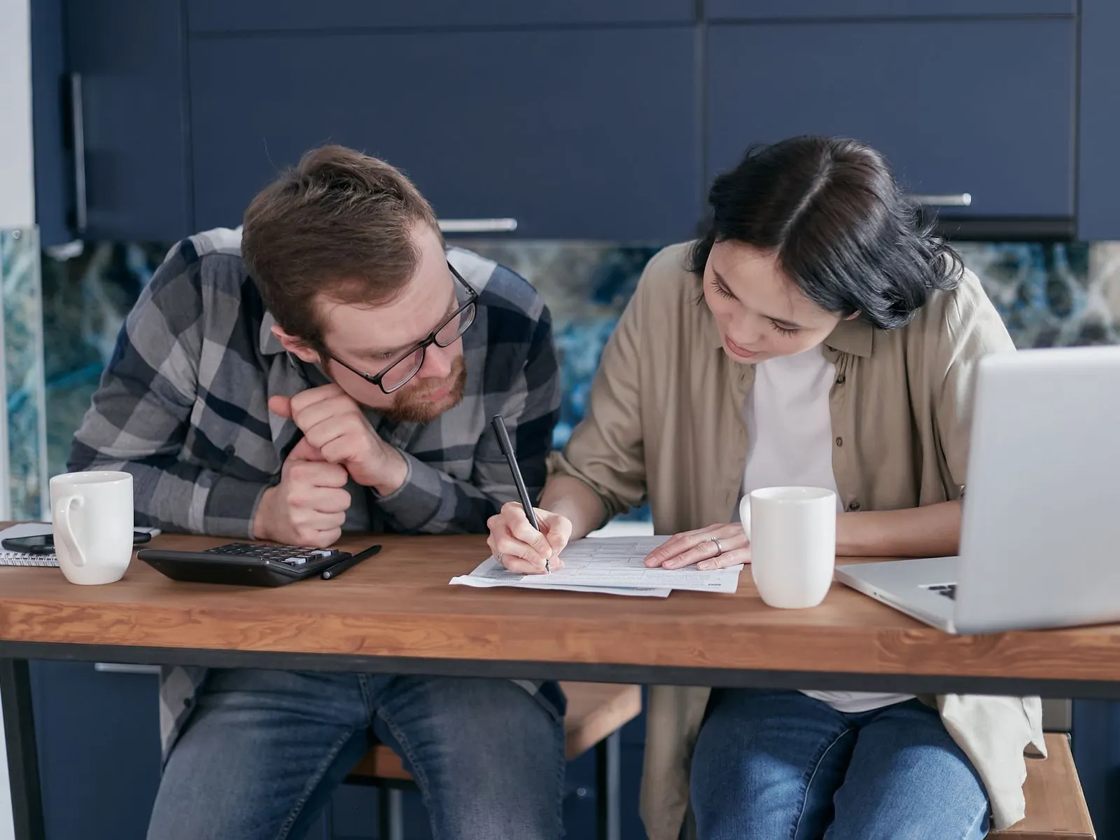 Couple working through paperwork together at a wooden kitchen table
