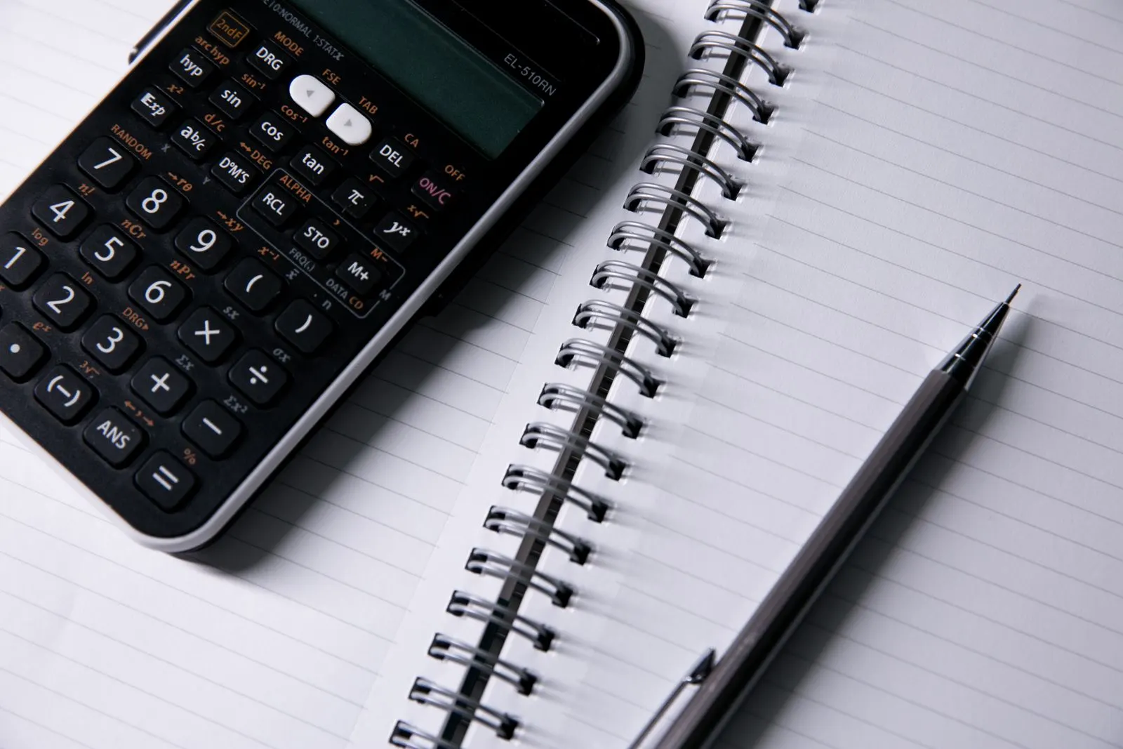 Open notebook, calculator and pen on a desk