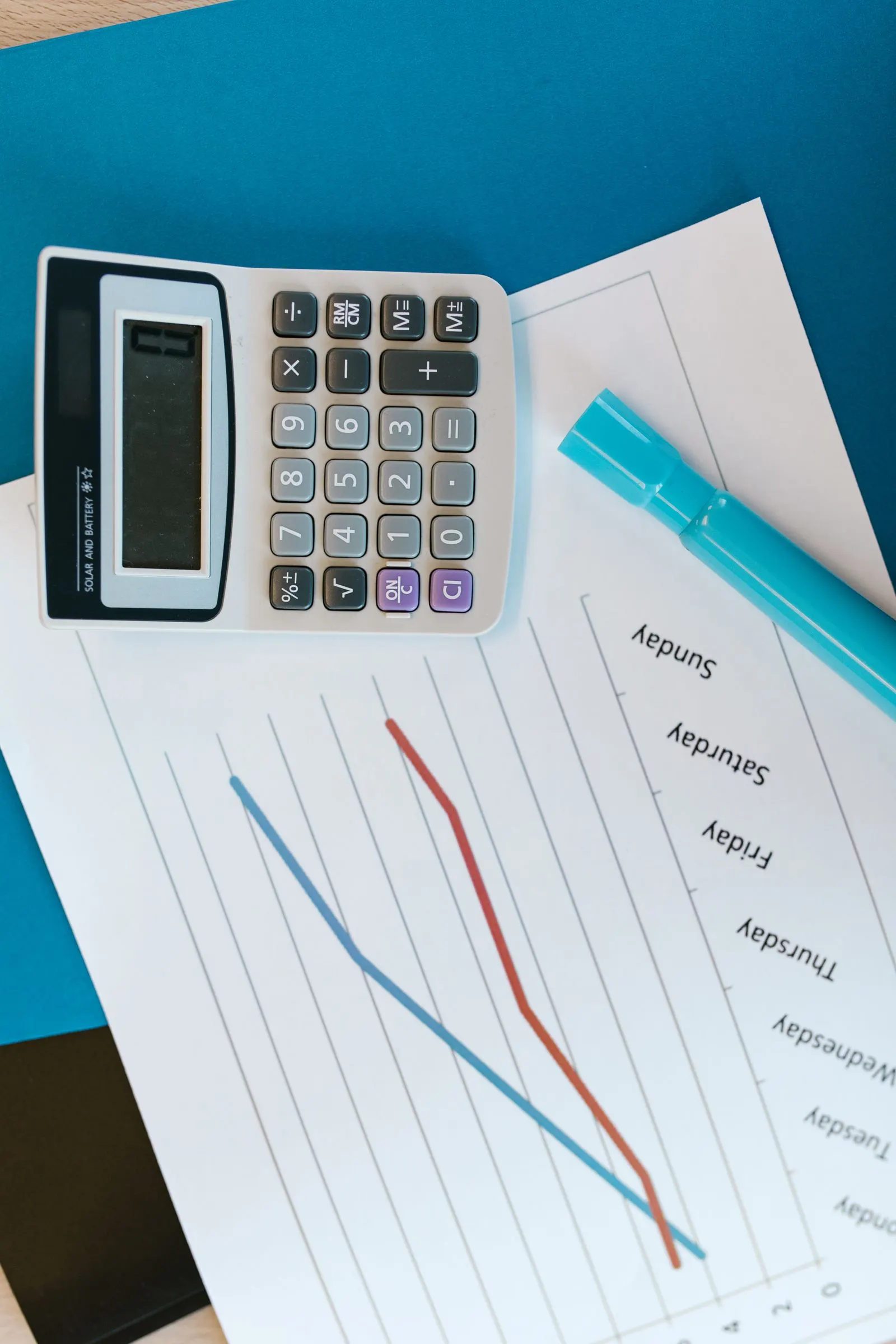 Top view of a desk with a calculator, graph papers and a marker