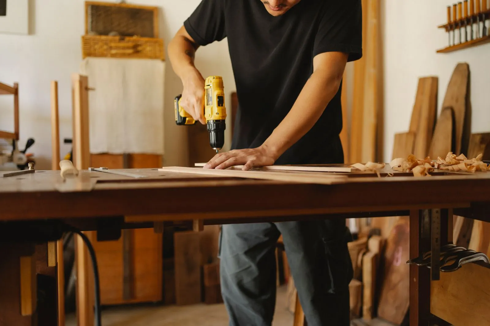 Close-up of a carpenter drilling a wooden plank at a workshop bench