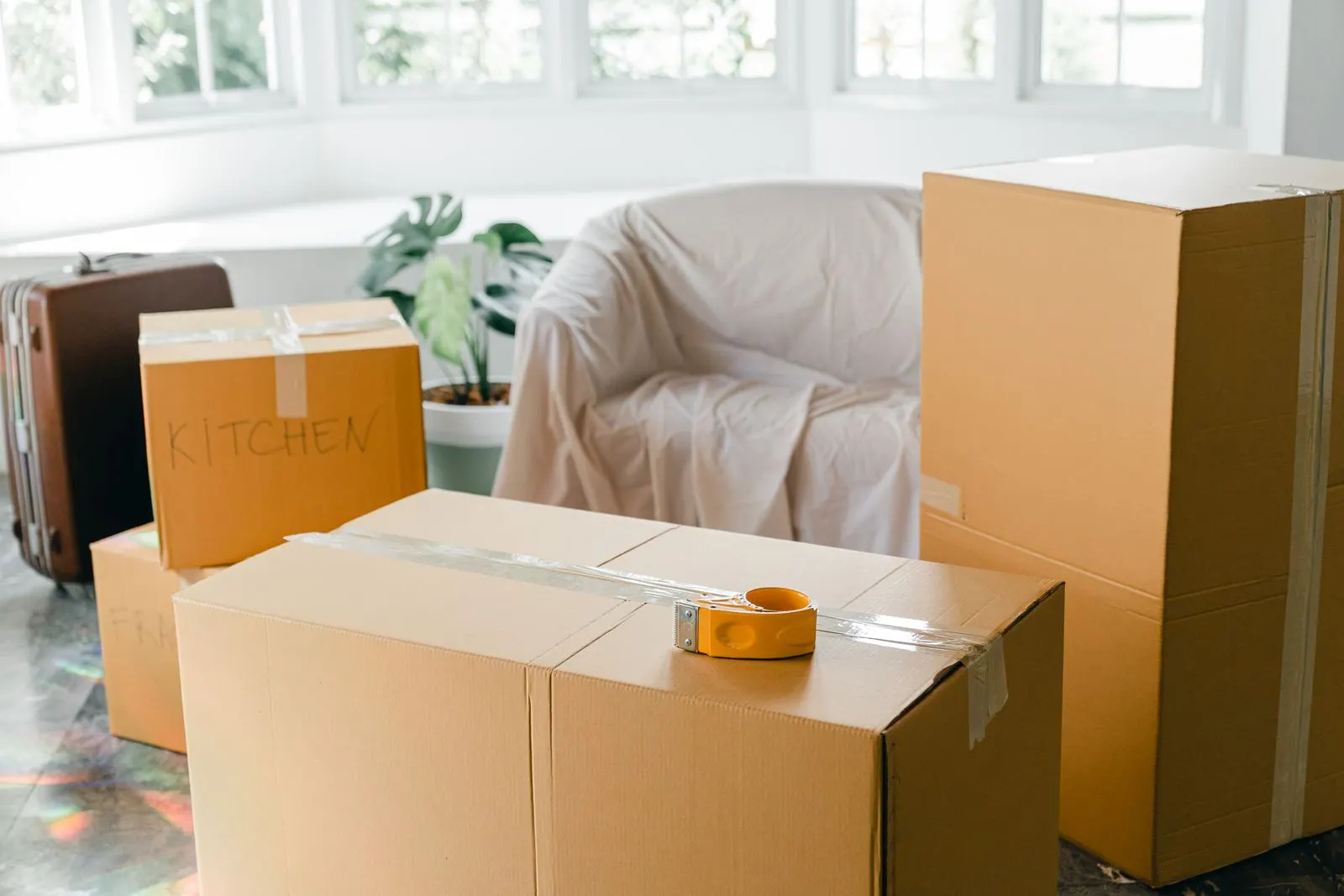 Packed cardboard boxes in a sunlit living room before a move